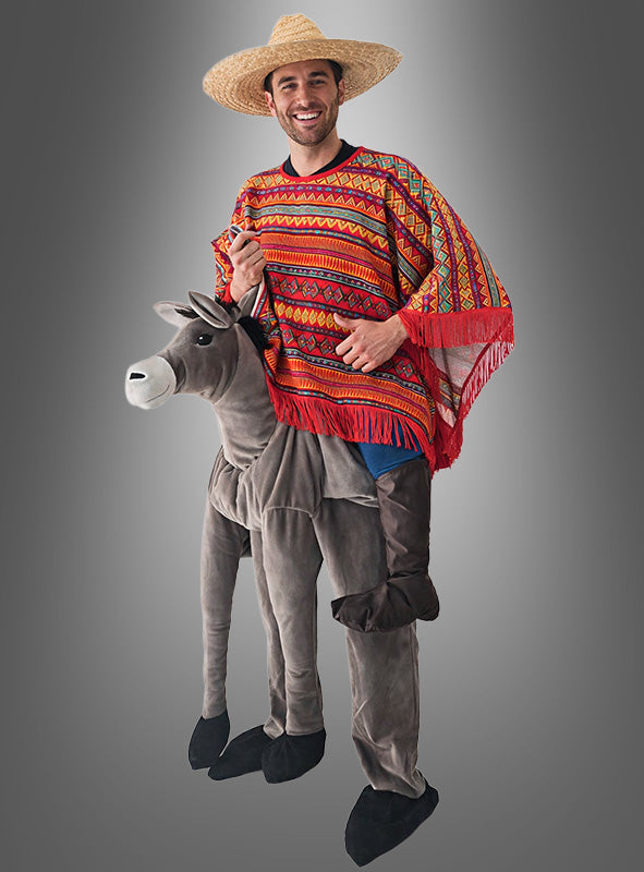 Eine Person trägt das „Mexikaner auf dem Esel“-Kostüm – ein Spaßkostüm mit einem bunten Poncho, einem Sombrero und der optischen Täuschung, auf einem grauen Esel zu reiten – und steht vor einem schlichten grauen Hintergrund.