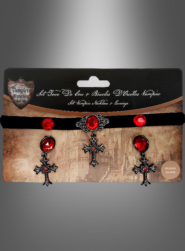 Das Set „Halloween-Schmuck: Kreuze mit roten Edelsteinen“ umfasst ein schwarzes Samt-Halsband, das mit einem roten Edelstein und einem Kreuzanhänger verziert ist, sowie dazu passende Ohrringe mit roten Edelsteinen und Kreuzmotiven. Das Ganze wird in einer Verpackung im Gothic-Stil präsentiert – das ideale Gothic-Schmuckset für Ihr Halloween-Schmuck-Set.