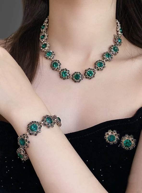 Eine Frau trägt das „Edles Schmuckset mit Strasssteinen, 4-teilig“ – ein passendes Set aus Halskette, Armband und Ohrringen mit funkelnden Strasssteinen und filigranen Details aus Gold und Silber –, das sich perfekt zur Vervollständigung Ihres 20er-Jahre-Kostüms eignet.