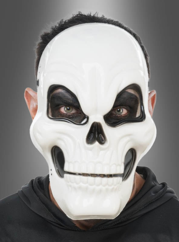 Eine Person, die die „Weiße Totenkopf-Halbmaske für Erwachsene“ und einen schwarzen Kapuzenpulli trägt, blickt vor einem schlichten grauen Hintergrund nach vorne.