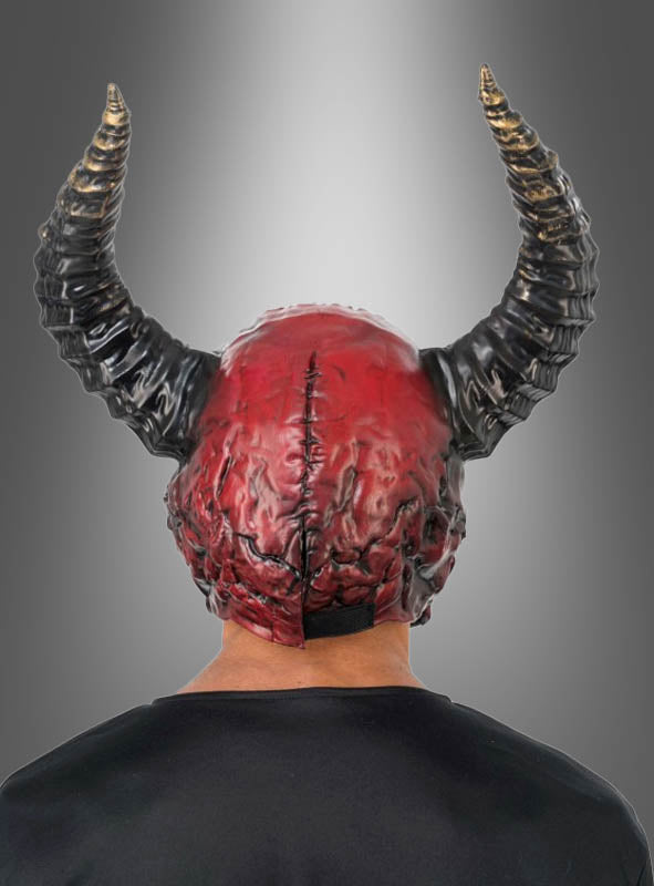 Eine Person, die die auffällige „Roter Dämon mit Hörner Maske Deluxe“ trägt – eine rot-schwarze Vollgesichtsmaske mit Hörnern –, ist von hinten vor einem grauen Hintergrund mit Farbverlauf zu sehen.