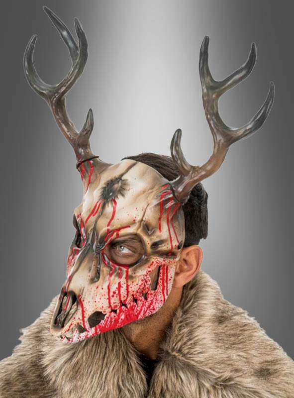 Eine Person, die die „Blutiger Hirsch Skelett-Maske“ trägt – einen pelzartigen Umhang, ein detailreiches Hirschschädel-Design mit Kunstblut, naturgetreues Geweih und aufwendig gestaltete Horror-Merkmale – steht vor einem grauen Hintergrund mit Farbverlauf. Perfekt für eine unvergessliche Halloween-Verkleidung oder als auffälliges Accessoire in Form einer Tierschädel-Maske aus Schaumstoff.