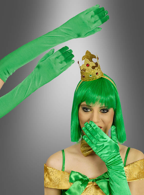 Eine Person mit grüner Perücke, goldener Krone und goldenem Kleid, die extra lange grüne Satinhandschuhe (47 cm) trägt, hält sich die Hand vor den Mund; zwei Hände in denselben grünen Handschuhen ragen vor diesem grauen Hintergrund empor.