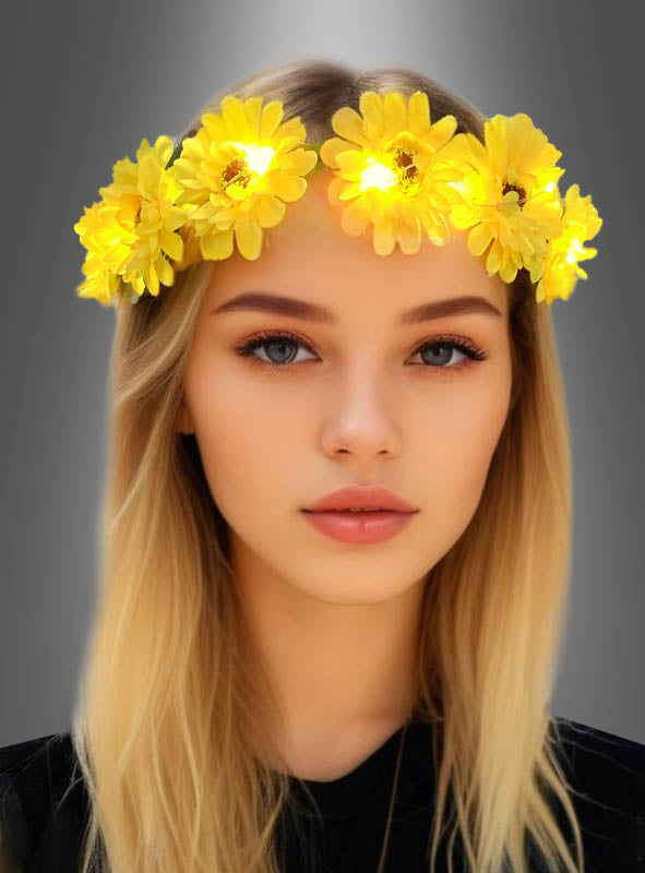 Eine Frau mit langen blonden Haaren trägt einen leuchtend gelben „Sonnenblumen“-Haarkranz mit LED und ein schwarzes Oberteil vor einem grauen Hintergrund mit Farbverlauf – ein auffälliges Haarschmuckstück, das ihrem Look einen verspielten Hippie-Kostüm-Touch verleiht.