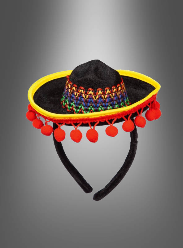 Mini-Sombrero für eine Mexikanerin – ein kleiner schwarzer Sombrero, verziert mit gelber Borte, roten Pompons und einem bunt gewebten Band – das ideale Accessoire für ein Mexikanerin-Kostüm, präsentiert vor einem grauen Farbverlauf.
