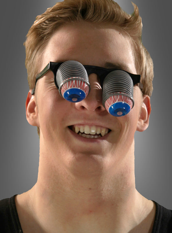 Eine Person, die die „Spaßbrille mit herausfallenden Augen“ trägt, die mit plastikartigen, slinky-ähnlichen Federn und übertrieben großen, nach außen ragenden Augäpfeln versehen ist. Die Person lächelt und blickt in die Kamera, wodurch sich dieses Accessoire perfekt für Partybrillen oder Karnevalskostüme eignet.