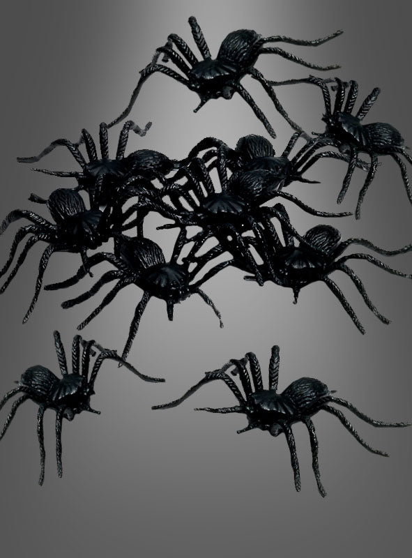 Ein Set aus 12 Plastikspinnen (5 cm) ist vor einem grauen Hintergrund mit Farbverlauf angeordnet und verleiht Ihrer Halloween-Dekoration den perfekten gruseligen Touch.