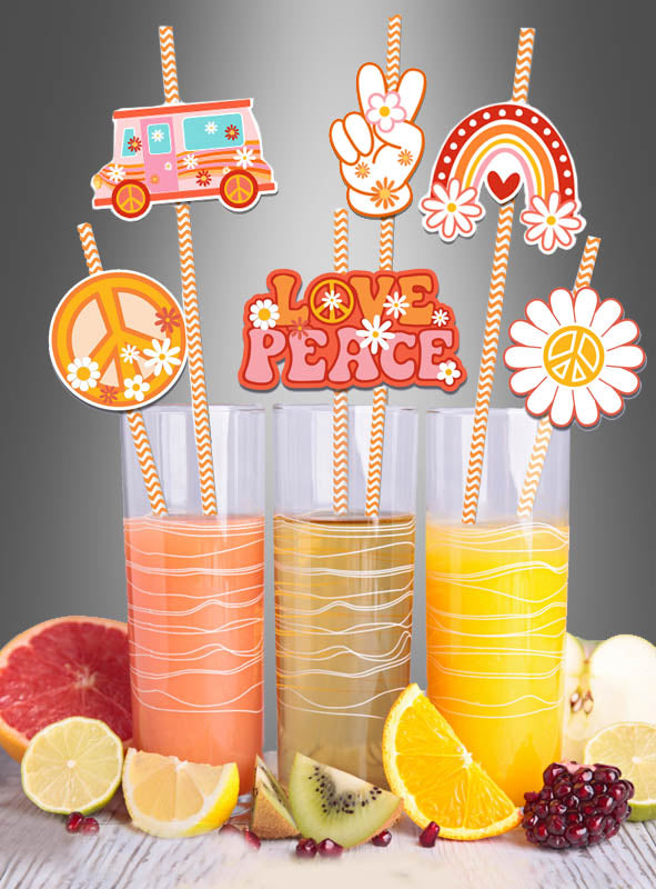 Drei Gläser Saft mit orange gestreiften Strohhalmen „Hippie Party“ (36 Stück) und farbenfrohen Dekorationen im Stil der 1960er Jahre. Vor den Gläsern sind Zitrusfrüchte und Granatapfelstücke angerichtet – perfekt für jede Hippie-Mottoparty.