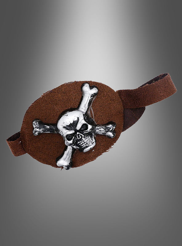 Die „Totenkopf-Augenklappe braun“ ist eine braune Augenklappe mit einem metallischen Totenkopf-Emblem auf der Vorderseite, die mit einem elastischen Band befestigt wird – ideal als Augenklappe mit Totenkopf für Ihr nächstes Piraten-Outfit – dargestellt vor einem grau verlaufenden Hintergrund.