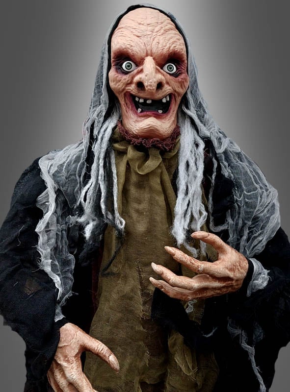 Eine Person in einem detailreichen Hexenkostüm mit übertriebenen Gesichtszügen, zerfetzten Kleidern, einer grauen Perücke und langen Fingern steht vor einem grauen Hintergrund und ähnelt der animatronischen Hexenfigur 160 cm für Halloween – eine ideale Dekoration für jede Halloween-Feier.