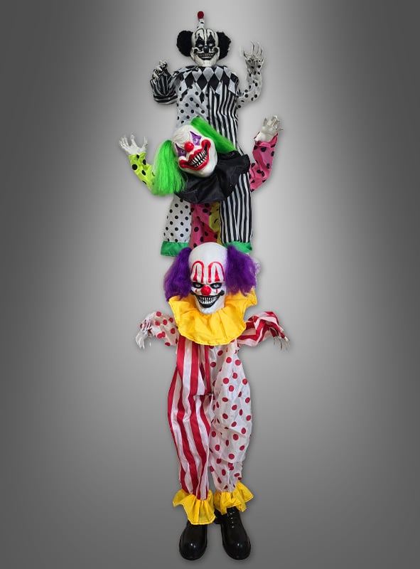 Drei furchterregende Clownfiguren mit übertriebenem Make-up und farbenfrohen Kostümen sind vor einem grauen Hintergrund vertikal aufgereiht und sorgen so für eine unheimliche Atmosphäre. Die „Clown Deko Akrobaten 180 cm mit Bewegungsmelder“ ist die perfekte animierte Clown-Dekoration, um Ihrem Geisterhaus oder Ihrer Party eine gruselige Note zu verleihen.
