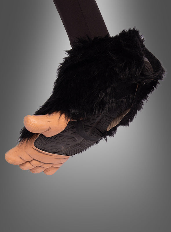 Eine Hand, die die „Schimpansenfüße für Affenkostüme“ trägt – ein großer, realistisch gestalteter Handschuh in Form eines menschlichen Fußes mit schwarzem Kunstfell am Handgelenk –, perfekt, um ein Affenkostüm zu vervollständigen oder als verspielte Schimpansen-Schuhe für Erwachsene zu dienen.
