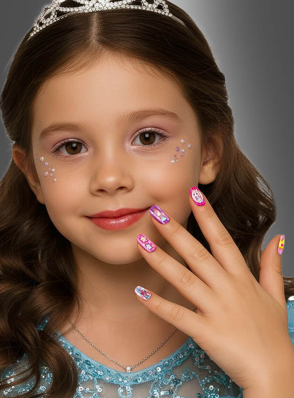 Ein kleines Mädchen mit welligem braunem Haar, gekleidet in ein blaues Kleid und eine Tiara, präsentiert stolz ihre wunderschön verzierten rosa „Kleine Prinzessin Kinder Nägel selbstklebend, 12 Stück“; die selbstklebenden Nägel aus dem Prinzessinnen-Set passen perfekt zu den funkelnden Strasssteinen auf ihren Wangen.