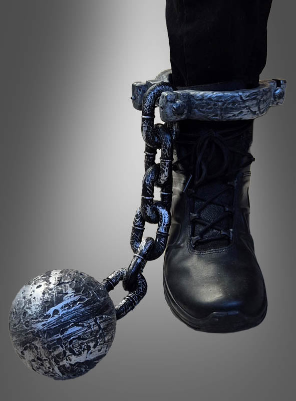 Eine Person, die schwarze Stiefel trägt, hat die „Fußfessel mit Kugel“ – eine Metallfessel am Knöchel mit einer schweren Kette und einer Kugel –, die sich perfekt als Accessoire für einen Junggesellenabschied oder als krönender Abschluss Ihres Häftlingskostüms eignet.