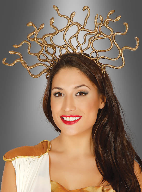 Eine Frau, die den goldenen „Medusa Schlangen Kopfschmuck“ trägt – inspiriert von Medusas legendärem Schlangenhaar – und dazu ein weiß-goldenes Outfit trägt, lächelt vor einem grauen Hintergrund mit Farbverlauf.
