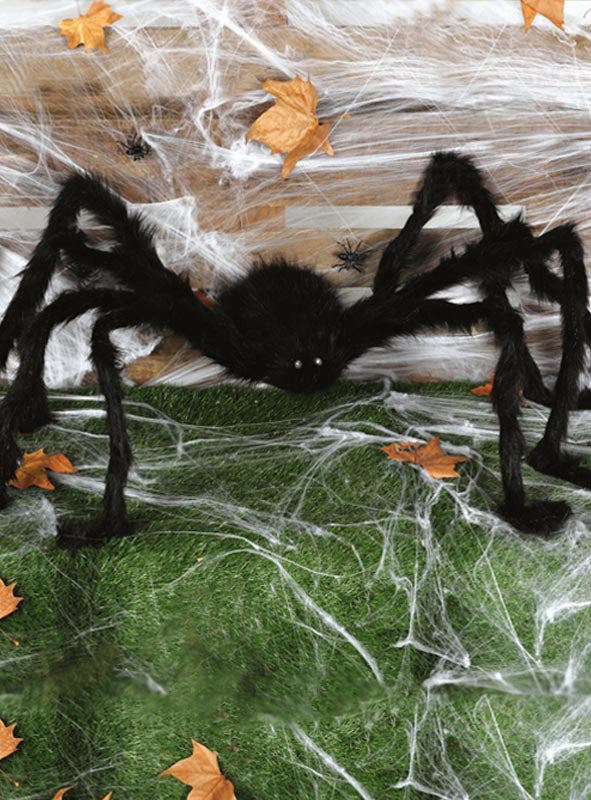 Überlebensgroße Spinne (150 cm) mit LED-Augen in Schwarz auf grünem Gras, mit weißen künstlichen Spinnweben und verstreuten Herbstblättern – perfekt als Halloween-Spinne oder gruselige Spinnendekoration für Ihre festliche Dekoration.