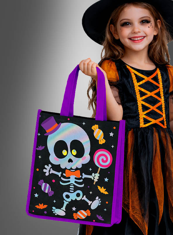 Ein lächelndes Kind in einem Hexenkostüm hält die Halloween-Sammeltasche „Lustiges Skelett“ in der Hand, die mit einem Comic-Skelett, Bonbons und Fledermäusen verziert ist – bereit, leckere Halloween-Süßigkeiten zu sammeln.