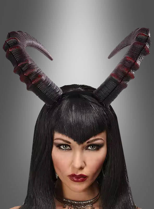 Eine Frau mit langen schwarzen Haaren und auffälligem Make-up trägt einen strukturierten, schwarz-roten „Hörner“-Haarreif (Cosplay, Unisex) als markantes Halloween-Accessoire auf dem Kopf, vor einem grau verlaufenden Hintergrund.