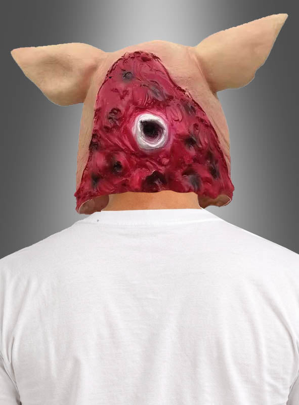 Eine Person, von hinten gesehen, die die „Blutige Latexmaske Schwein“ trägt, eine Schweinemaske mit einer freiliegenden, roten Scheinjwunde und einem runden Auge auf der Rückseite.