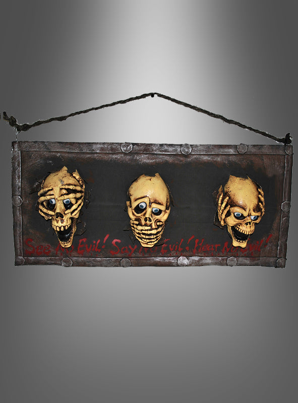 Ein Wandbild, das „Die drei Schädel“ (40 x 90 cm), zeigt drei gelbe Totenköpfe mit ausdrucksstarken Gesichtern und blauen Augen vor einem dunklen Hintergrund, akzentuiert durch einen kräftigen roten Schriftzug mit der Aufschrift „See Evil! Say Evil! Hear No Evil!“. Dieses einzigartige Wandbild verleiht Ihrer Halloween-Dekoration den perfekten verspielten Touch und ist eine kreative Hommage an die ikonische „Drei-Affen“-Dekoration.