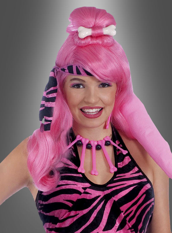 Eine Person, die die „Pinke Perücke mit Knochen Steinzeit“ trägt, dazu ein Kostüm als „Steinzeitfrau“ mit Zebrastreifen und eine rosa Knochenkette, lächelt vor einem grauen Hintergrund mit Farbverlauf.