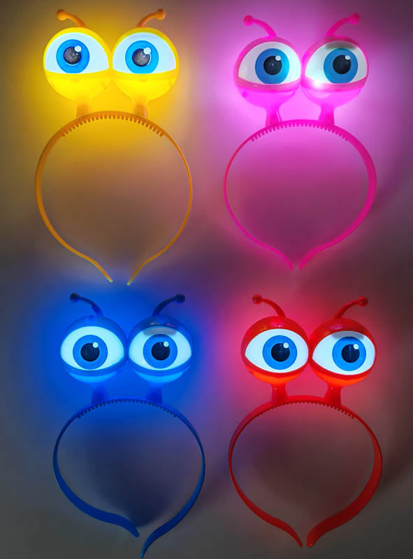 Vier bunte LED-Haarreifen im „Alien-Augen“-Stil mit großen Comic-Augen und leuchtenden Antennen in Gelb, Rosa, Blau und Rot, die in einem Rastermuster auf einem einfarbigen Hintergrund angeordnet sind.