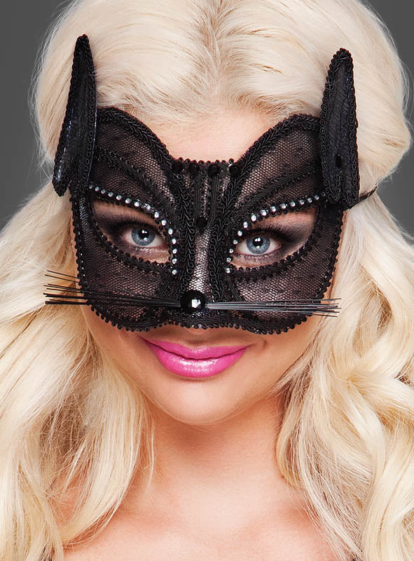 Eine Frau mit langen blonden Haaren trägt die „Schwarze Augenmaske Katze“ – eine von einer schwarzen Katze inspirierte Maskenballmaske mit verspielten Ohren, funkelnden Strasssteinen und künstlichen Schnurrhaaren –, dazu leuchtend pinken Lippenstift. Sie blickt vor einem neutralen Hintergrund in die Kamera, wodurch sich dieser Look ideal für jeden Maskenball oder jede Kostümparty eignet.
