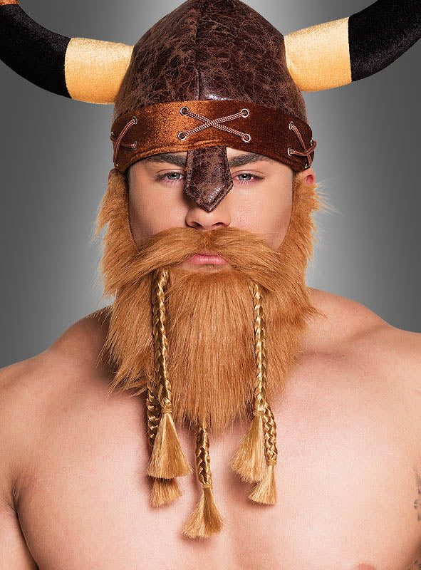 Eine Person, die einen Wikingerhelm mit Hörnern und einen künstlichen roten Wikinger-Vollbart mit Zöpfen trägt und direkt in die Kamera blickt.