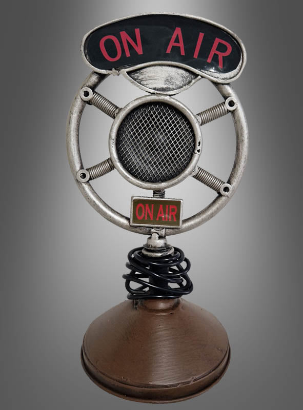 Mikrofon-Dekoration im Stil der 20er Jahre aus Metall mit rundem Metallrahmen und „ON AIR“-Schriftzug oben in der Mitte, auf braunem Sockel vor grauem Hintergrund – perfekt als authentisches Mikrofon im Stil der 20er Jahre oder als Vintage-Mikrofon-Dekoration für Ihre Party im Stil der 20er Jahre.