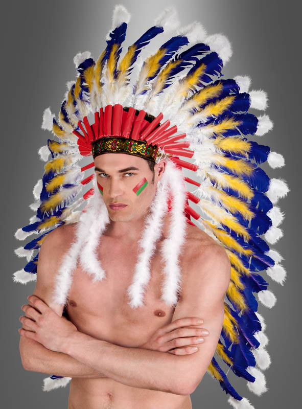Eine Person mit nacktem Oberkörper, die den „Deluxe Häuptling Indianer Federschmuck“ trägt – einen auffälligen Kopfschmuck, der mit roten, gelben, blauen und weißen Federn verziert ist –, steht mit verschränkten Armen vor einem grauen Hintergrund mit Farbverlauf. Dieser luxuriöse Kopfschmuck unterstreicht perfekt die imposante Ausstrahlung ihres einzigartigen Indianerkostüms.