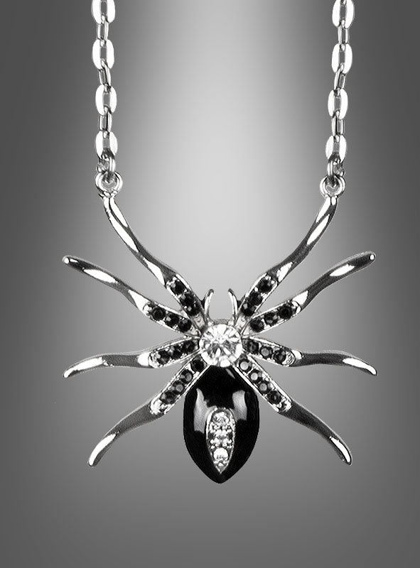 Silberkette mit Spinne und Edelsteinen: Dieser exquisite silberne Anhänger in Spinnenform, verziert mit schwarzen und klaren Edelsteinen, hängt elegant an einer Kette und ist ein auffälliges Statement-Stück unter den Spinnenschmuckstücken. Vor einem grau abgestuften Hintergrund präsentiert, ist er perfekt, um Ihrer Halloween-Schmuckkollektion einen Hauch von geheimnisvoller Eleganz zu verleihen.
