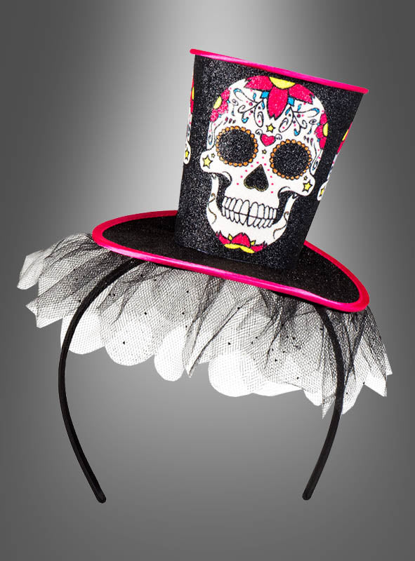Schwarzes Stirnband, verziert mit dem „Tag der Toten“-Mini-Zylinder – einem kleinen Zylinder mit einem farbenfrohen Zuckerschädel-Motiv, rosa Besatz und schwarzem Netz-Tüll.