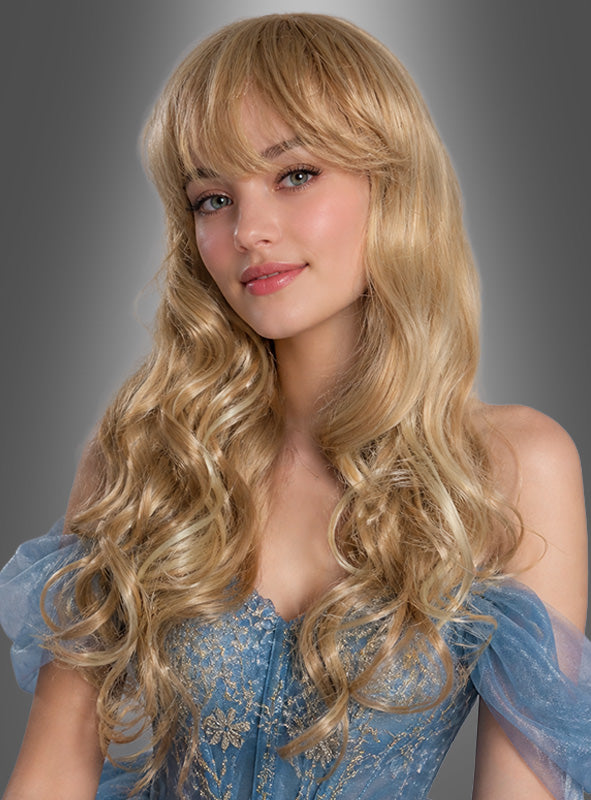Eine junge Frau mit langen, welligen blonden Haaren, die der Langhaar-Perücke „Linda Blond“ ähneln, trägt ein blaues schulterfreies Kleid und posiert vor einem grauen Hintergrund mit Farbverlauf – perfekt, um Deluxe-Perücken-Modelle zu präsentieren oder Inspiration für Karnevalskostüme zu liefern.