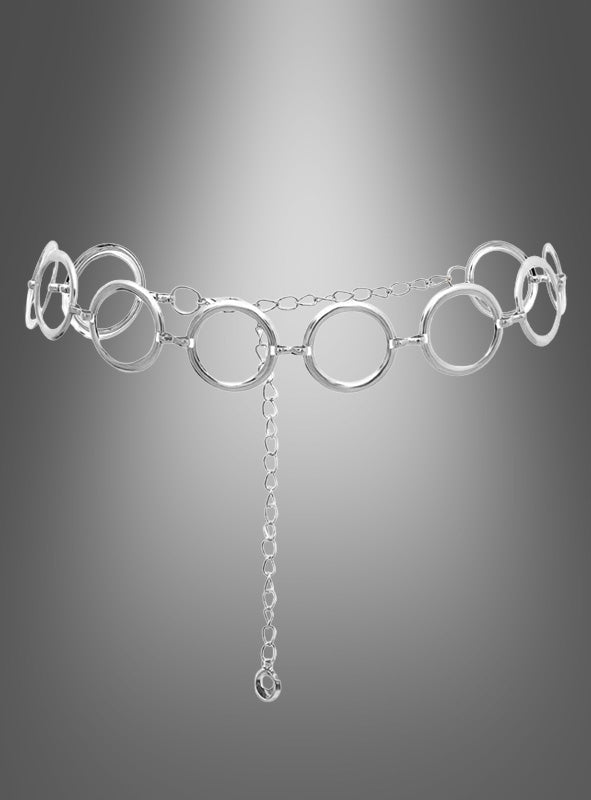 Der Retro-Gürtel „Silber Hüftgürtel“ besticht durch große, miteinander verbundene Ringe und eine herabhängende Kette und ist damit das perfekte Accessoire, um Ihr Outfit im Stil der 60er- und 70er-Jahre abzurunden. Hier ist er vor einem grau verlaufenden Hintergrund abgebildet.