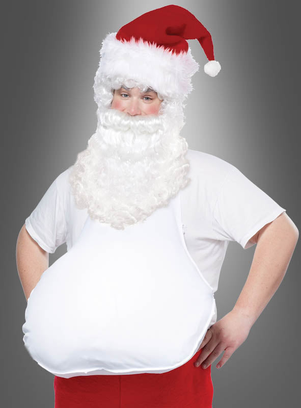 Eine Person in einem Weihnachtsmannkostüm mit roter Mütze, weißem Lockenbart und einem übertrieben großen Bauch, der mithilfe des Accessoires „Schürze für dicken Nikolaus-Bauch“ erzeugt wurde, steht vor einem einfarbigen grauen Hintergrund.