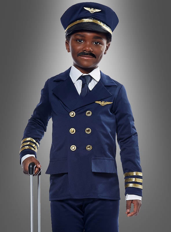 Ein Kind, das ein Flugzeugkapitän-Kostüm für Kinder mit goldenen Knöpfen und Streifen trägt, eine dazu passende Mütze auf dem Kopf hat und den Griff eines Koffers in der Hand hält, steht vor einem grauen Hintergrund.