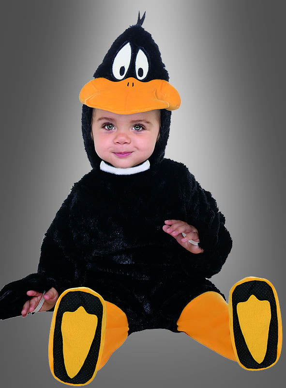 Ein Baby, das ein schwarz-gelbes Daffy-Duck-Baby-Entenkostüm trägt, sitzt vor einem grauen Hintergrund mit Farbverlauf und schaut in die Kamera.