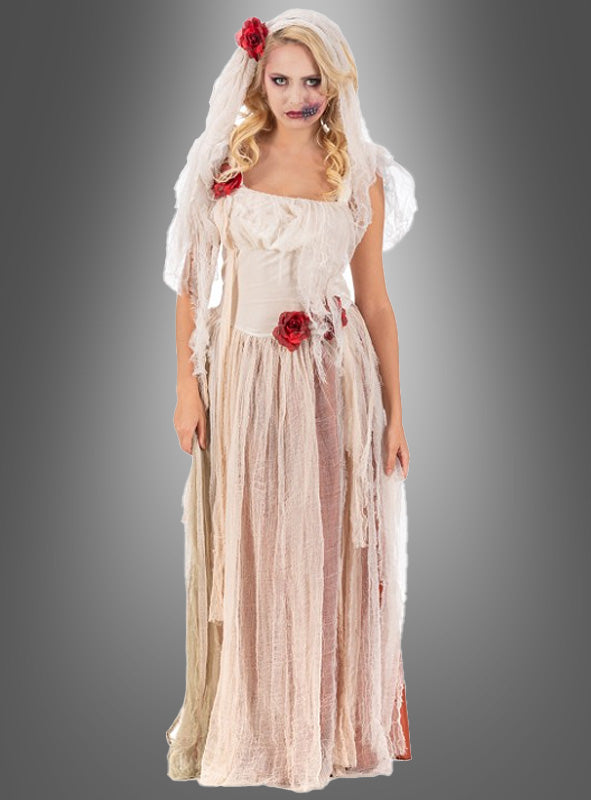Eine Frau in einem zerfetzten weiß-beigen Brautkleid mit roten Rosen, Schleier und Zombie-Make-up steht vor einem grauen Hintergrund mit Farbverlauf – perfekt für alle, die im unvergesslichen „Zombiebraut“-Kostüm „Cristina“ den gespenstischen Geist von Halloween heraufbeschwören möchten.