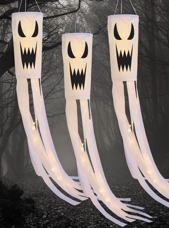 Drei Geist-Windsäcke mit Geistermotiv als Halloween-Gartendekoration mit LED-Beleuchtung, verziert mit schwarzen, grimmigen Gesichtern und langen weißen Bändern, hängen in einer nebligen, dunklen Waldkulisse und sorgen so für eine unheimliche Halloween-Atmosphäre. Diese LED-Windsäcke eignen sich perfekt als Halloween-Akzente in der Gartendekoration, um Ihrem Außenbereich einen gruseligen Touch zu verleihen.