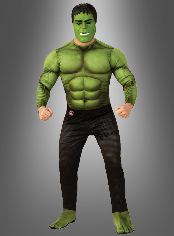Eine Person, die das grüne „Hulk Muskelkostüm Endgame für Erwachsene“-Superheldenkostüm trägt, komplett mit passender Gesichtsbemalung, steht mit geballten Fäusten vor einem grauen Hintergrund.