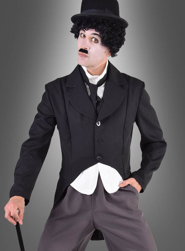 Eine Person, die das „Charlie Komiker“-Kostüm im Frack-Stil trägt – ein klassisches, von Charlie Chaplin inspiriertes Ensemble bestehend aus einem schwarzen Anzug, einer Melone, einem Spazierstock, einem aufgemalten Schnurrbart und weißer Gesichtsbemalung –, steht vor einem grauen Hintergrund; eine ideale Wahl für den Karneval für Herren oder alle, die ein Kostüm einer ikonischen Figur aus dem Stummfilm suchen.