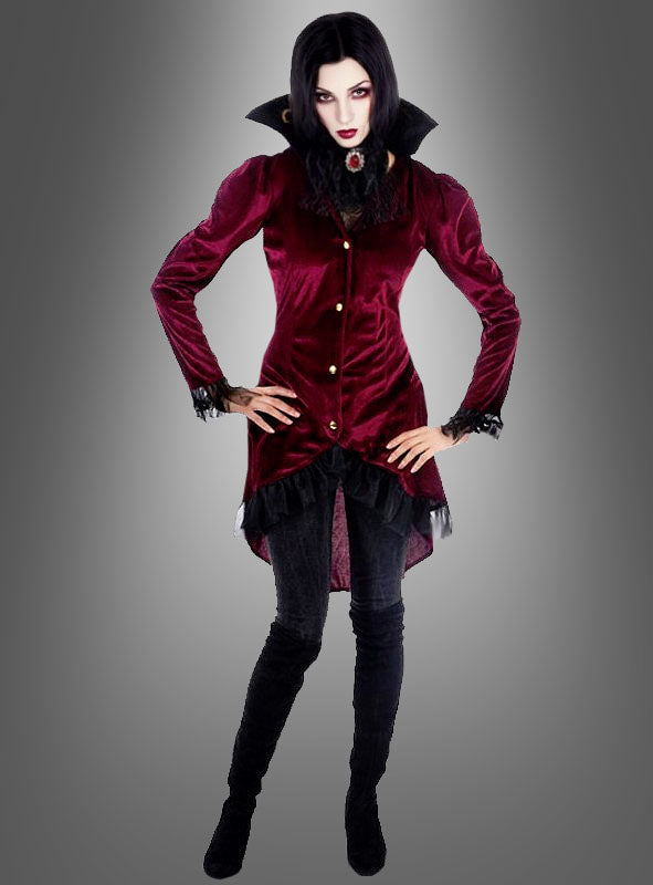 Das Model trägt die „Wandelbare Kostümjacke Vampirin Jasna“, kombiniert mit einer schwarzen Hose und Stiefeln, und steht mit den Händen in den Hüften vor einem grauen Hintergrund mit Farbverlauf.