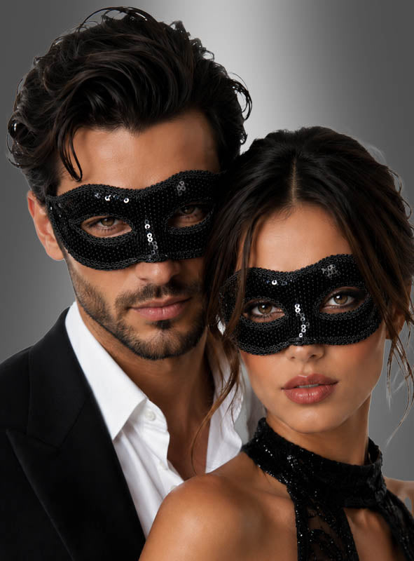 Ein Mann und eine Frau, die schwarze „Venezianische Masken mit Pailletten“ tragen, posieren gemeinsam vor einem grauen Hintergrund.