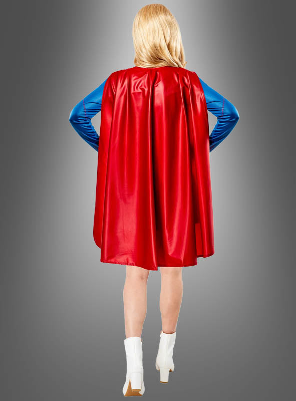 Eine Person, die das Supergirl-Kostüm für Damen von DC Comics trägt – bestehend aus einem blau-roten Anzug mit rotem Umhang und weißen Stiefeln –, steht mit den Händen in den Hüften und dem Rücken zur Kamera.