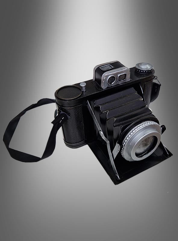 Eine Kamera im Stil der 20er Jahre – diese schwarz gehaltene Klappkamera im Vintage-Stil verfügt über einen Trageriemen, einen ausgezogenen Balgen und ein metallisches Objektiv und wird kunstvoll vor einem grau verlaufenden Hintergrund präsentiert. Sie ist das perfekte Kostümaccessoire für Liebhaber und Sammler, die auf der Suche nach einem authentischen Vintage-Fotoapparat-Schatz sind.