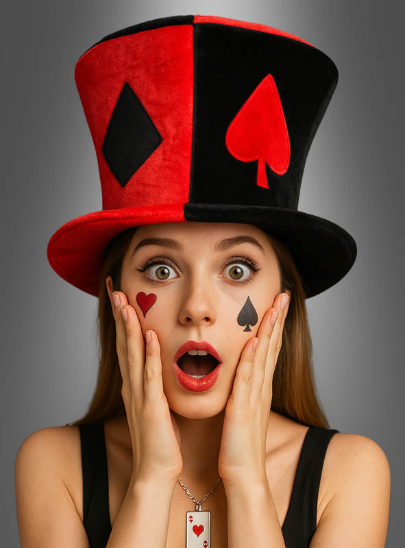 Eine Frau trägt den „Casino Stoff Zylinder schwarz-rot“, einen auffälligen schwarz-roten Zylinder, der mit Kartensymbolen verziert ist, dazu passend ist ihr Gesicht mit den entsprechenden Kartensymbolen bemalt. Mit den Händen an den Wangen sieht sie überrascht aus – das perfekte Outfit für eine Las-Vegas-Party.