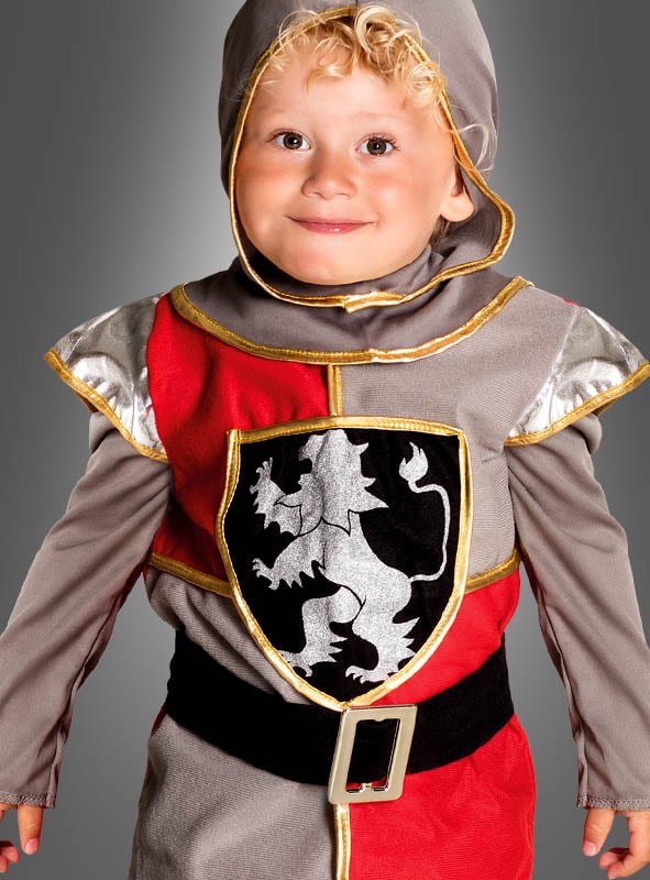 Ein kleines Kind im „Furchtloser Ritter“-Kinderkostüm, das auf der Brust ein markantes Löwenemblem trägt, lächelt vor einem grauen Hintergrund – ideal für jeden Kindergeburtstag oder um fantasievolle Ritterabenteuer anzuregen.