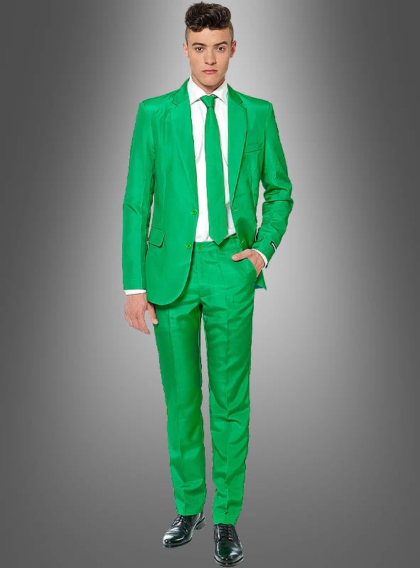 Ein Mann in einem grünen Herrenanzug von Suitmeister mit weißem Hemd und grüner Krawatte, eine Hand in der Hosentasche, vor einem grauen Hintergrund mit Farbverlauf. Dieses Outfit ist perfekt, um bei jeder Veranstaltung einen markanten Eindruck zu hinterlassen.