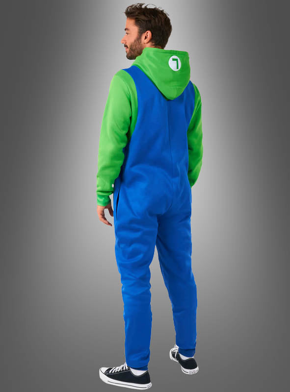 Ein Mann steht vor einem Hintergrund mit Farbverlauf und trägt den „Luigi-Overall für Erwachsene“, kombiniert mit einem grünen Hoodie, auf dessen Kapuze ein weißer Kreis und die Zahl 1 zu sehen sind – eine ideale Wahl für den Fasching oder als Teil eines Super-Mario-Kostüms –, dazu schwarze Sneaker; er steht mit dem Rücken zur Kamera.