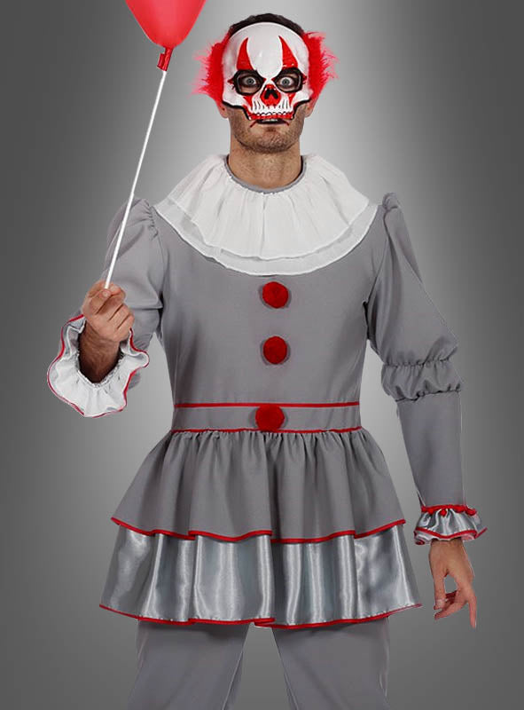 Eine Person im Halloween-Clown-Kostüm – aus grauem Stoff mit roten Verzierungen und Knöpfen – hält einen roten Luftballon in der Hand und trägt eine furchteinflößende weiß-rote Clownmaske mit leuchtend roten Haarbüscheln, während sie vor einem grauen Hintergrund steht. Dieses auffällige Outfit eignet sich perfekt für Halloween oder als unvergessliches Clown-Kostüm für Herren für jede gruselige Veranstaltung.